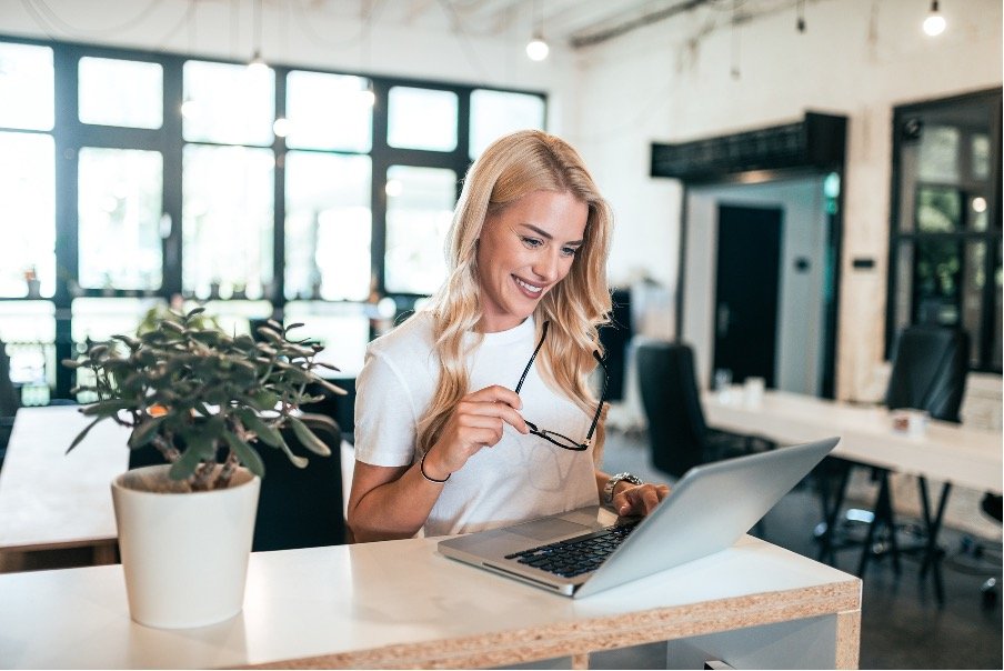 A wellness business owner working on a laptop in a bright office